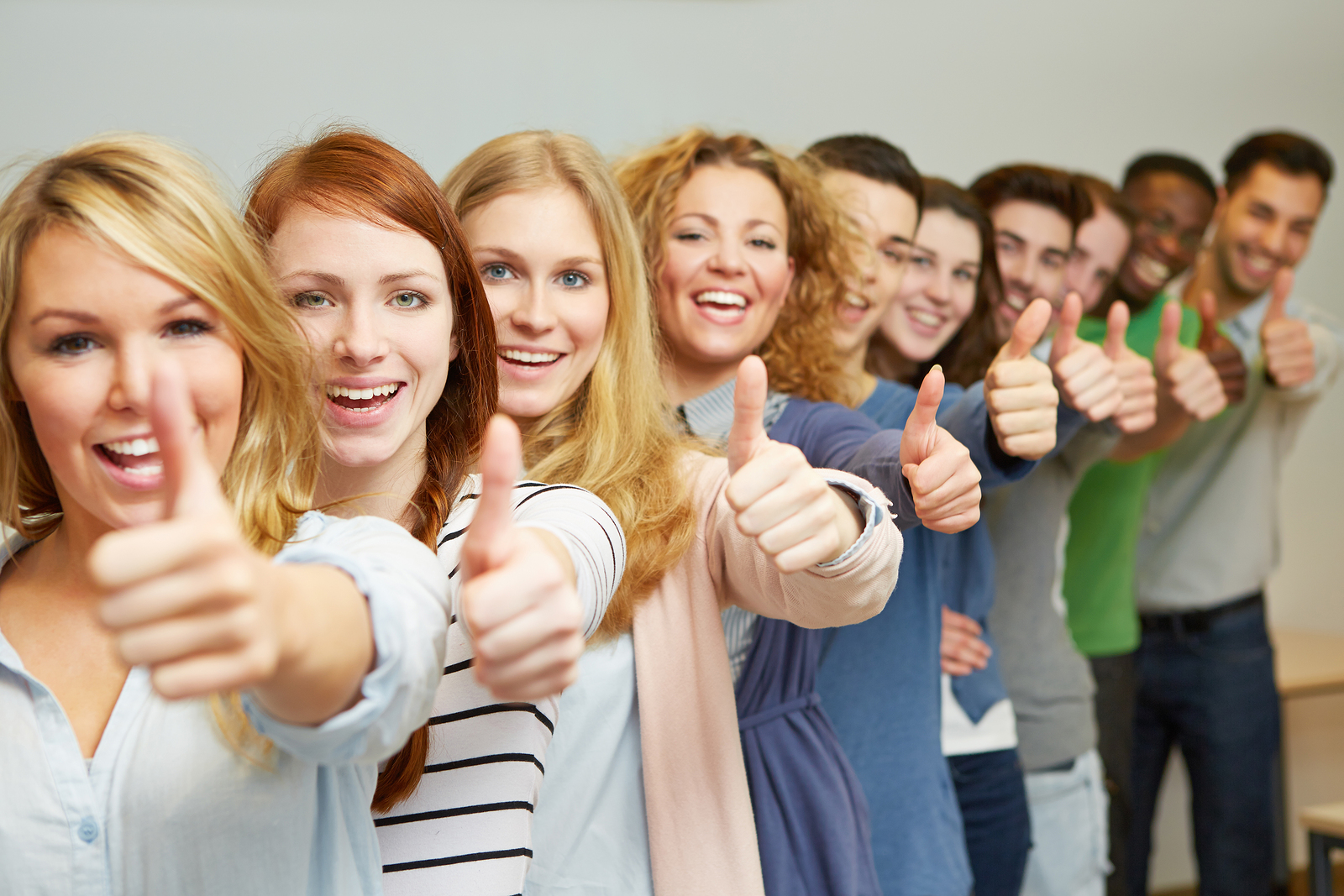 Many successful students holding thumbs up in a row